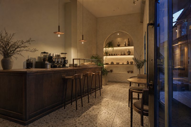 Açılış öncesi kafe içi: ceviz tezgâh, sarkıt aydınlatma, terrazzo zemin ve kemerli raf nişi